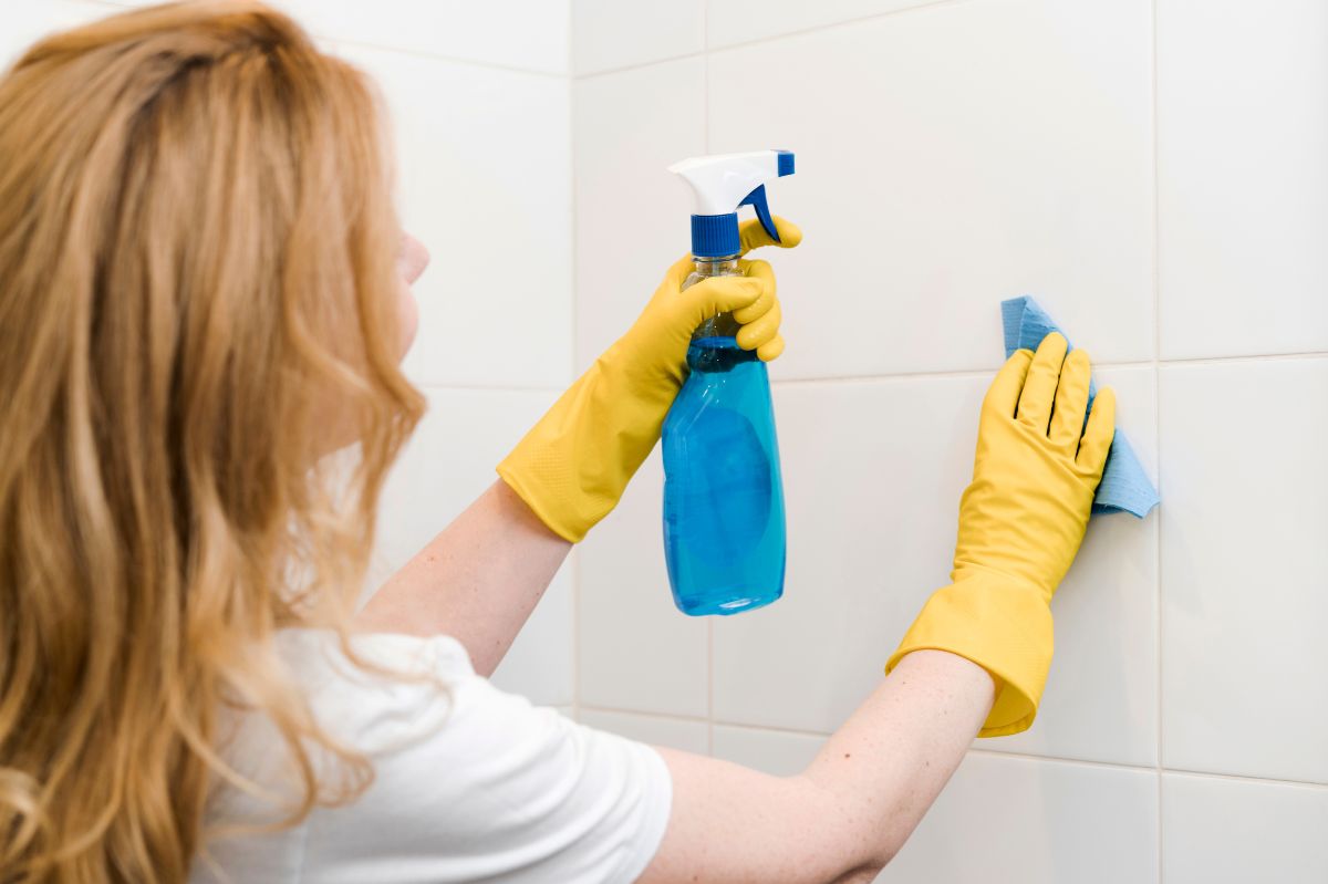 The woman is cleaning the bathroom tiles.