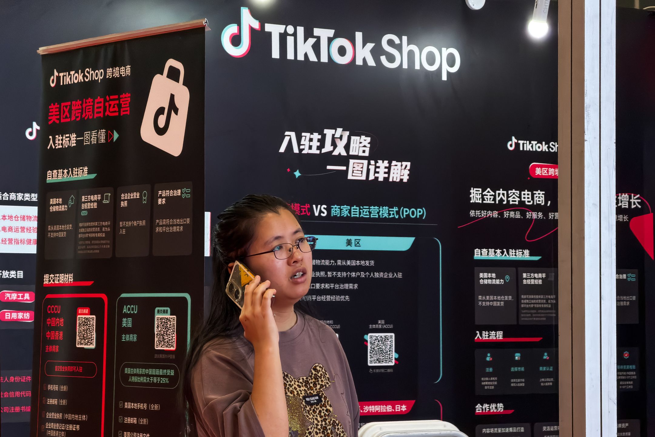 SHENZHEN, CHINA - APRIL 26: A staff member speaks on a phone at a booth promoting TikTok Shop cross-border e-commerce services during the Go Global Expo on April 26, 2026, in Shenzhen, Guangdong Province, China. Exhibitors at the event provide solutions to help businesses establish and manage TikTok Shop stores, supporting Chinese merchants in expanding into overseas markets through social commerce platforms. (Photo by Cheng Xin/Getty Images)