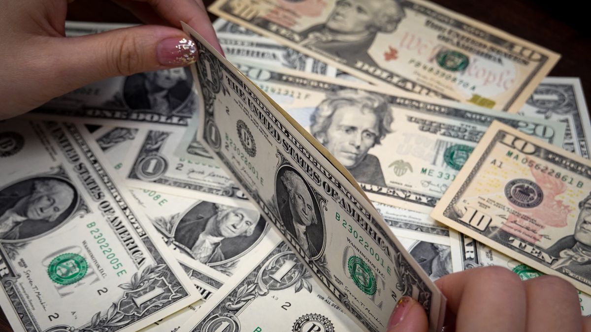 CHINA - 2024/09/15: In this photo illustration, a person picks U.S. dollar banknotes displayed on a table. (Photo Illustration by Sheldon Cooper/SOPA Images/LightRocket via Getty Images)