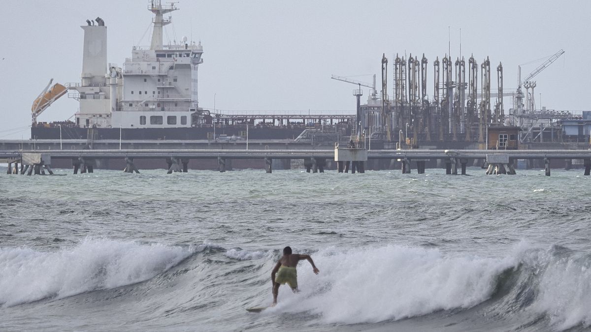 PUERTO CABELLO, VENEZUELA - DECEMBER 18: A man surfs as an oil tanker is seen anchored at the dock in the outskirts of 'El Palito' refinery on December 18, 2025 in Puerto Cabello, Venezuela. President Trump stated on December 17th that Venezuela took away oil rights from the US. Trump's administration has sanctioned Venezuelan oil with blockades, while many US Navy units are deployed off the coast of Venezuela under the premise of combating the drug cartels. (Photo by Jesus Vargas/Getty Images)