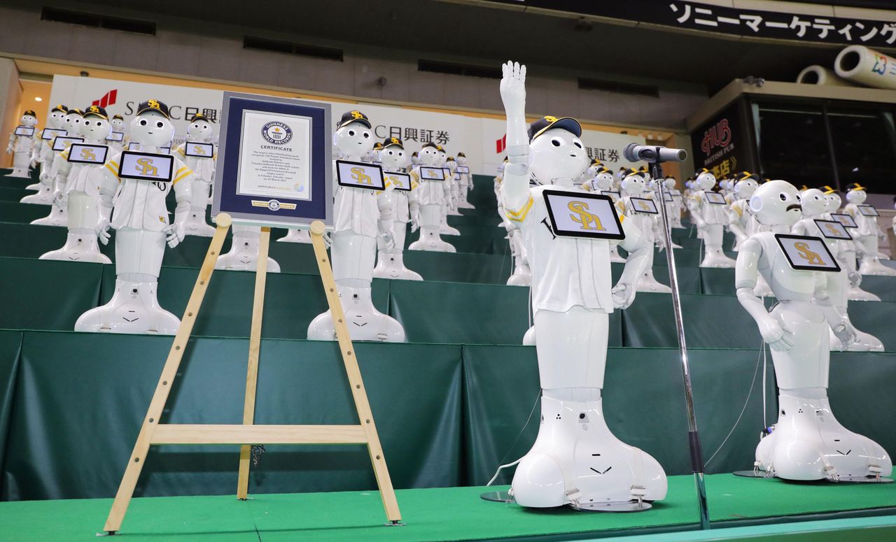 Roboty Pepper obok certyfikatu potwierdzającego rekord Guinnessa