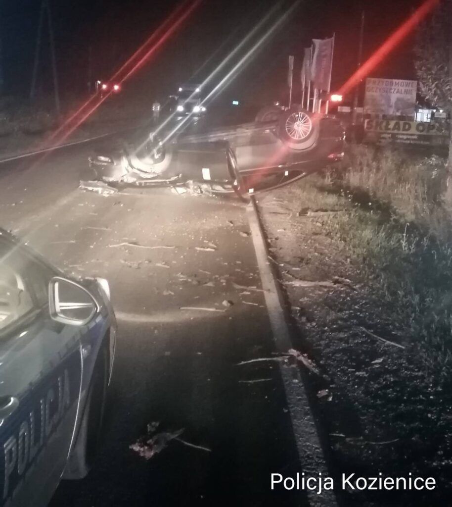 Na drodze leży przewrócone auto, a obok znajdują się resztki po wypadku i radiowóz policji.