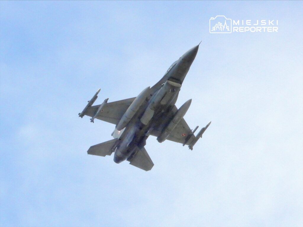 Myśliwiec F-16 przeprowadza manewr w powietrzu na tle błękitnego nieba.