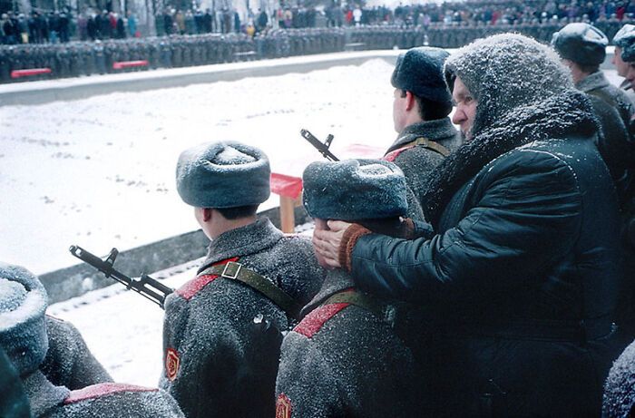 Babcia ogrzewa uszy swojego wnuka podczas poboru do armii. Wołgograd, Rosja, 1994