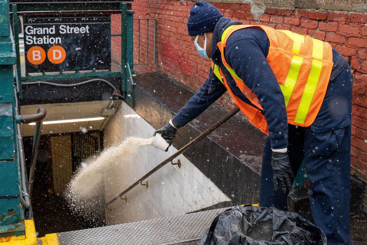 A New York City Transit worker throws salt on the steps of a subway entrance at the Grand St. station in Manhattan on Feb. 13 (Theodore Parisienne for New York Daily News/Tribune News Service via Getty Images)