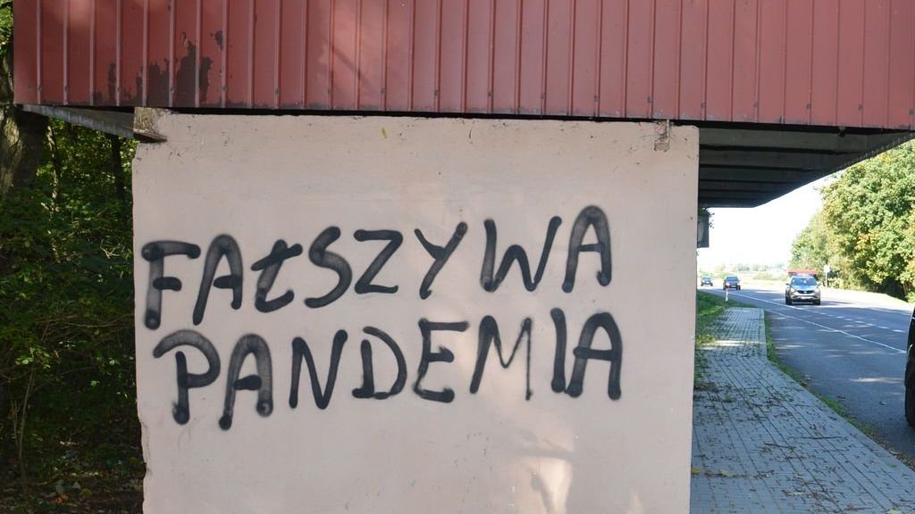 Napis "Fałszywa pandemia" na przystanku