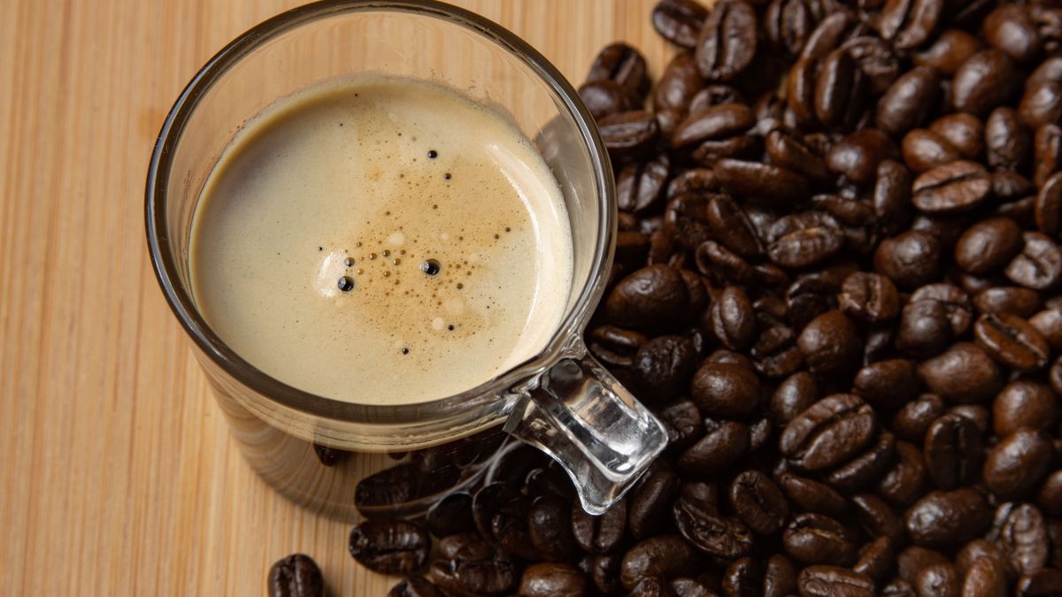 Raw organic Arabica variety coffee beans and a glass coffee mug on a wooden background. Amsterdam, The Netherlands on December 30, 2020 (Photo by Nicolas Economou/NurPhoto via Getty Images)