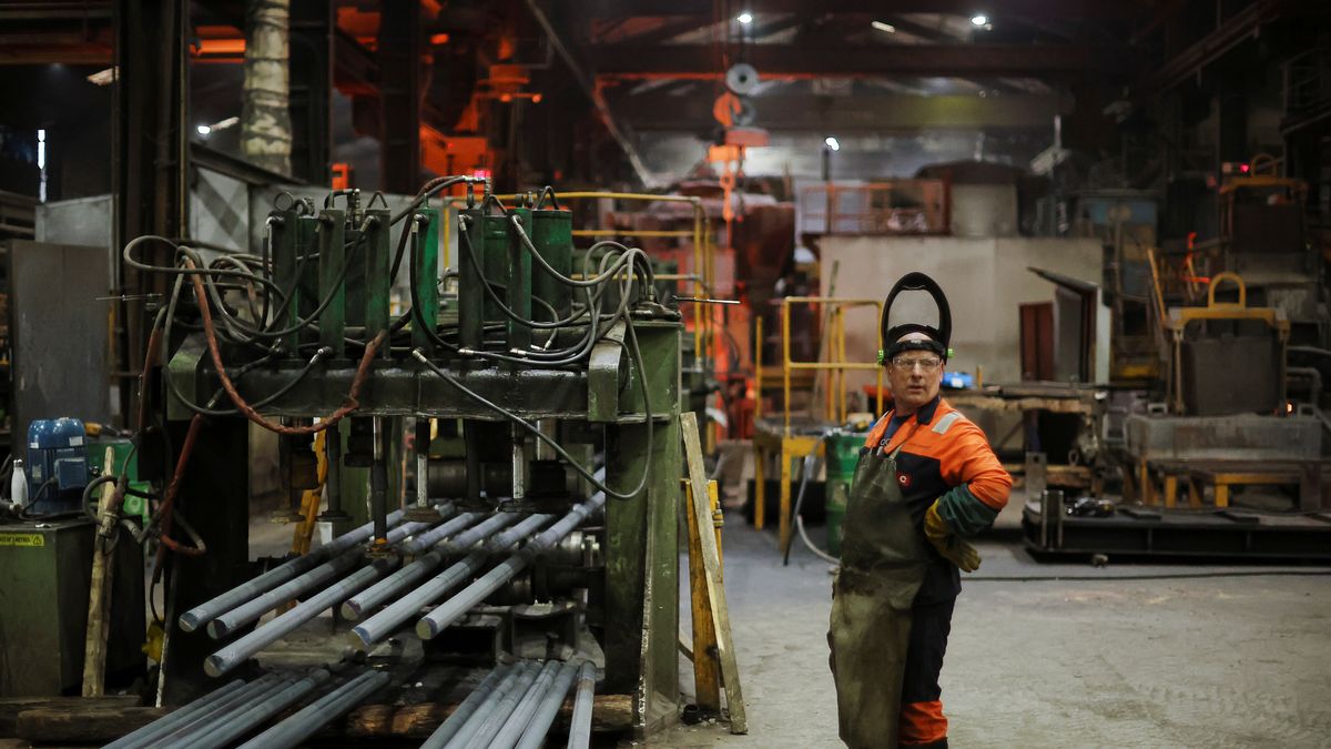 A worker stands next to a machine cutting newly manufactured bars of steel at the United Cast Bar Group's foundry in Chesterfield, Britain, April 12, 2022. Picture taken April 12, 2022.