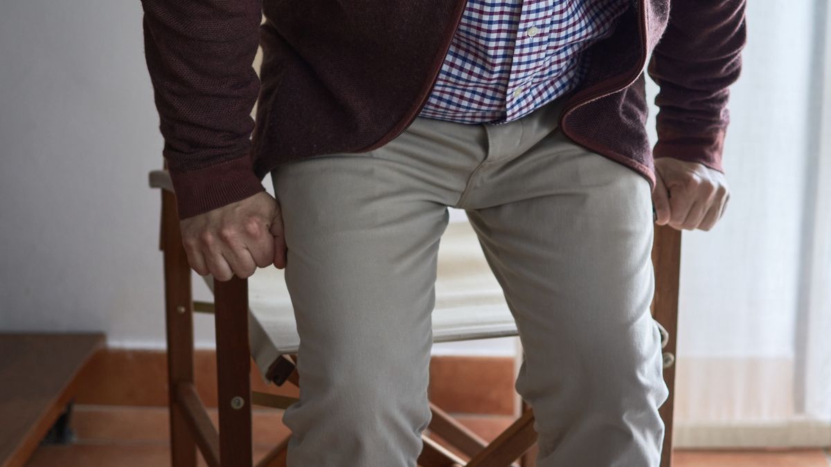 A mature man has difficulty getting up from an armchair in the living room of his home.Horizontal photo. Selective blur. A mature man has difficulty getting up from an armchair in the living room of his home.Juan Claudio Perez