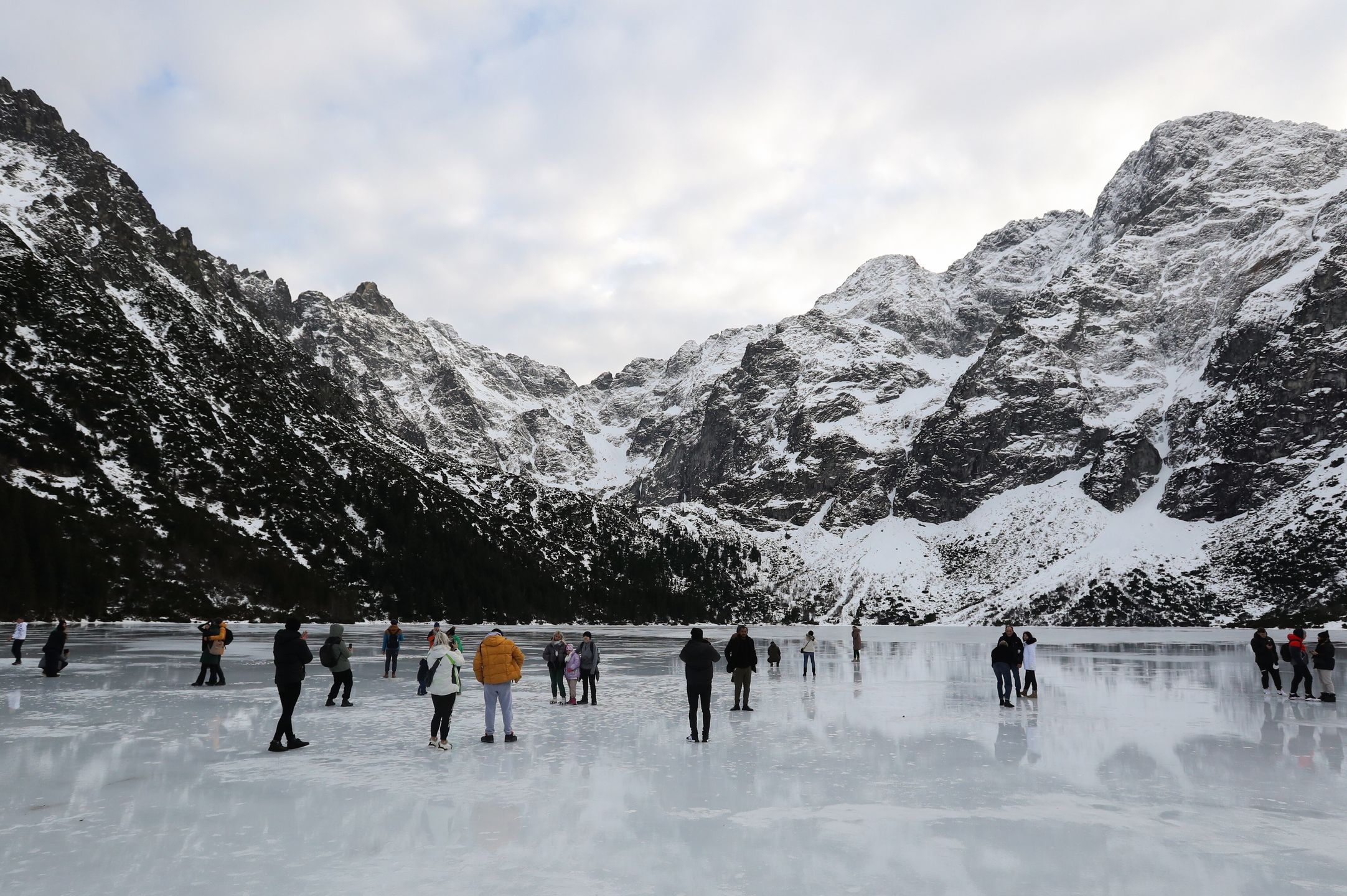 Tatry, Morskie Oko, 26.12.2022. Turyści na tafli lodu na jeziorze Morskie Oko w Tatrach, 26 bm. Tatrzański Park Narodowy ostrzega przed wchodzeniem na zamarznięte górskie jeziora � z powodu panujących w ciągu dnia dodatnich temperatur lód jest bardzo cienki i grozi załamaniem. (jm) PAP/Grzegorz Momot