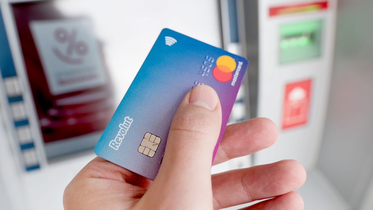 Revolut debit card in hand, ATM in backgroundWroclaw, Poland - NOV 06, 2019: Revolut debit card in hand, ATM in background. Revolut Ltd is a UK financial technology company that offers banking services.revolut, card, account, credit, debit, atm, cash, machine, travel, app, bank, service, exchange, money, logo, mastercard, currencies, multiple, banking, brand, closeup, cryptocurrency, currency, digital, illustrative, editorial, europe, finance, fintech, holiday, vacation, dollar, euro, mobile, multi, fee, prepay, screen, virtual, transfers, technology