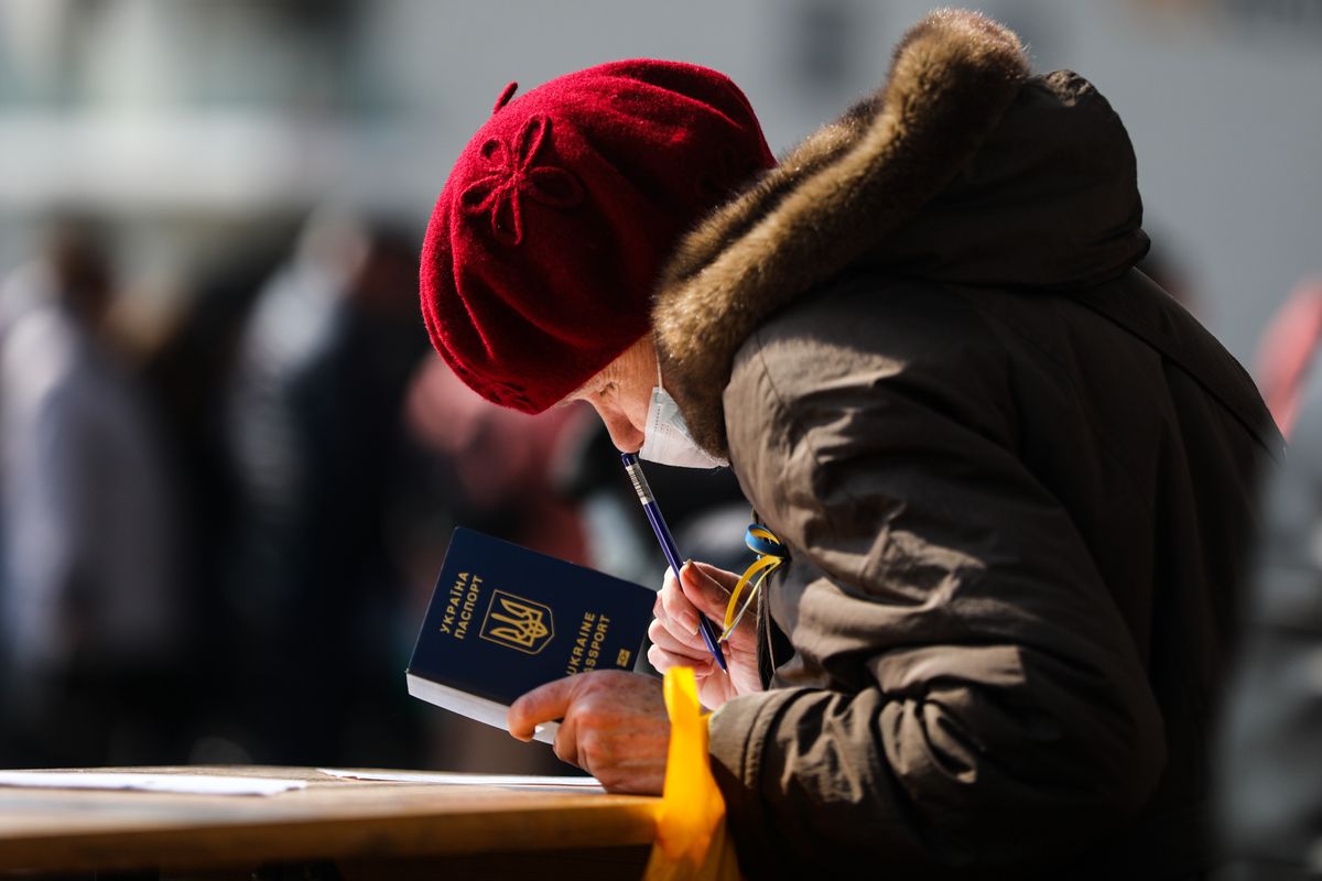 A woman is holding an Ukrainian passport while filling in documents before entering a register point at Tauron Arena where  refugees who fled from Ukraine can obtain a PESEL national identification number and remain in the country. Krakow, Poland on March 16, 2022. Russian invasion on Ukraine causes a mass exodus of refugees to Poland.   (Photo by Beata Zawrzel/NurPhoto via Getty Images)
