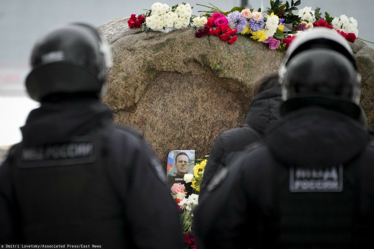 Policjanci przyglądają się, jak ludzie składają kwiaty, by oddać ostatni hołd Aleksiejowi Nawalnemu pod pomnikiem – dużym głazem z Wysp Sołowieckich