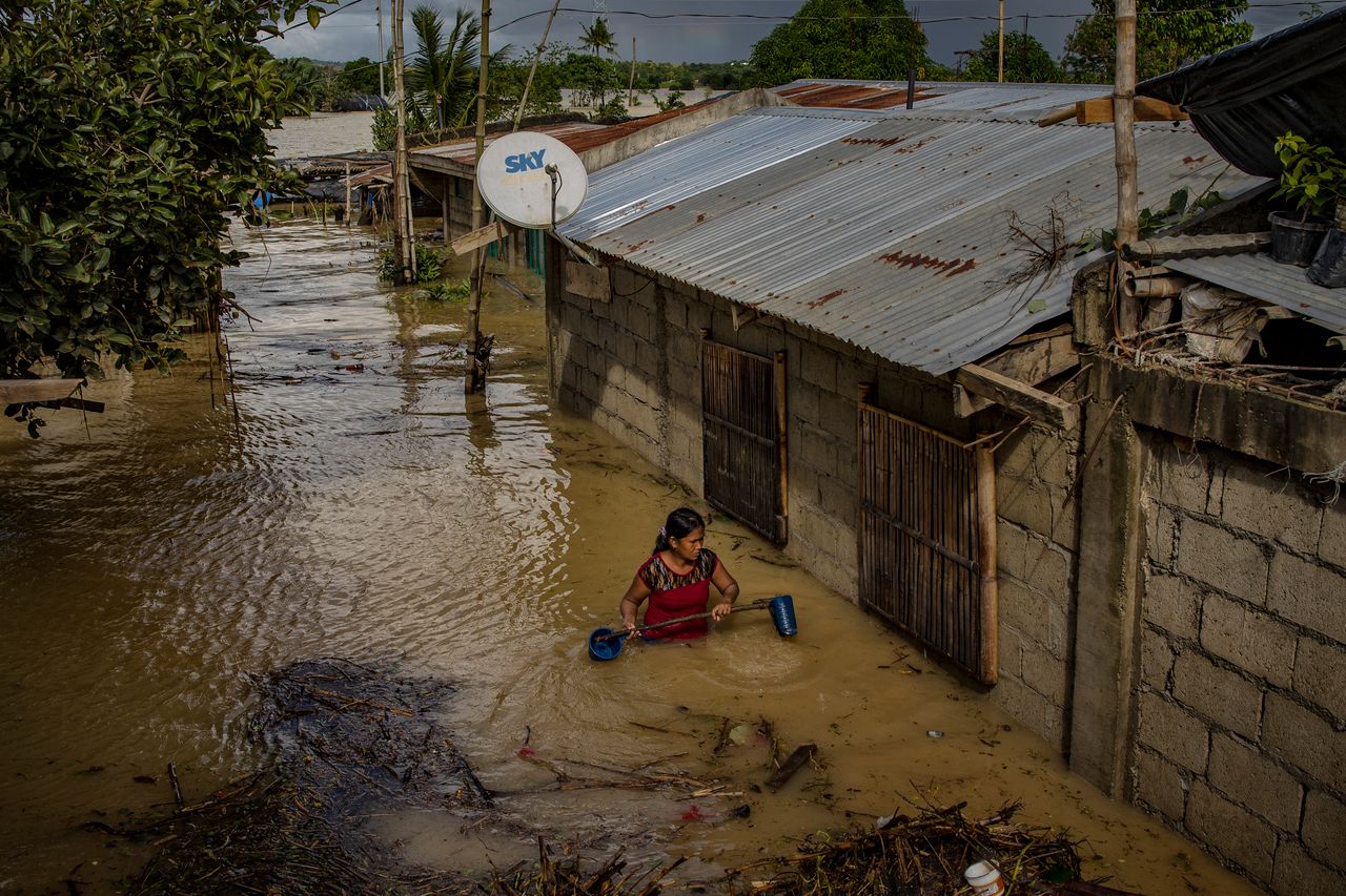 Kobieta przemierzająca zalaną filipińską wioskę (fot. Ezra Acayan)