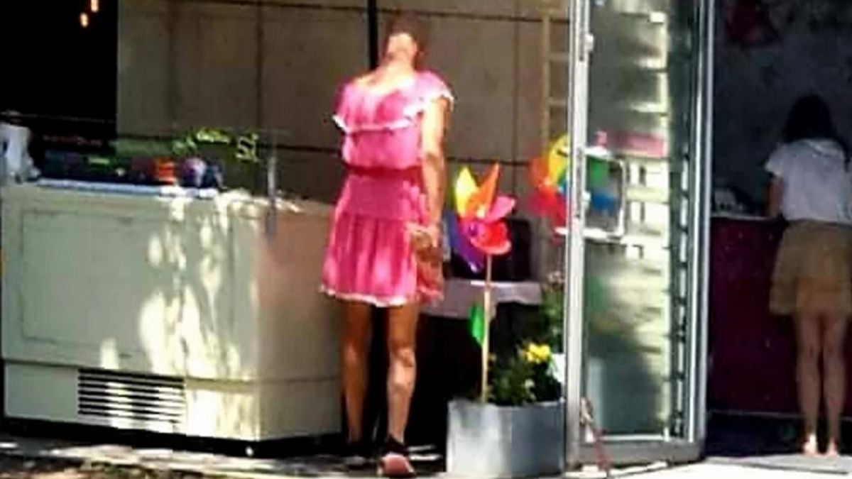 Mężczyzna w różowej sukience kradnący lody