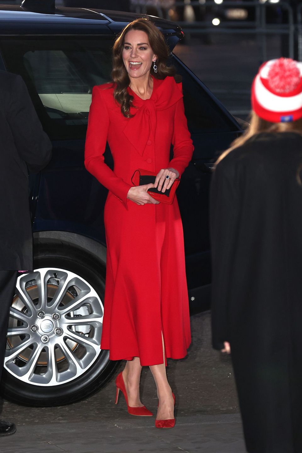 Kate Middleton w czerwonej sukience-płaszczu kolęduje z księciem Williamem