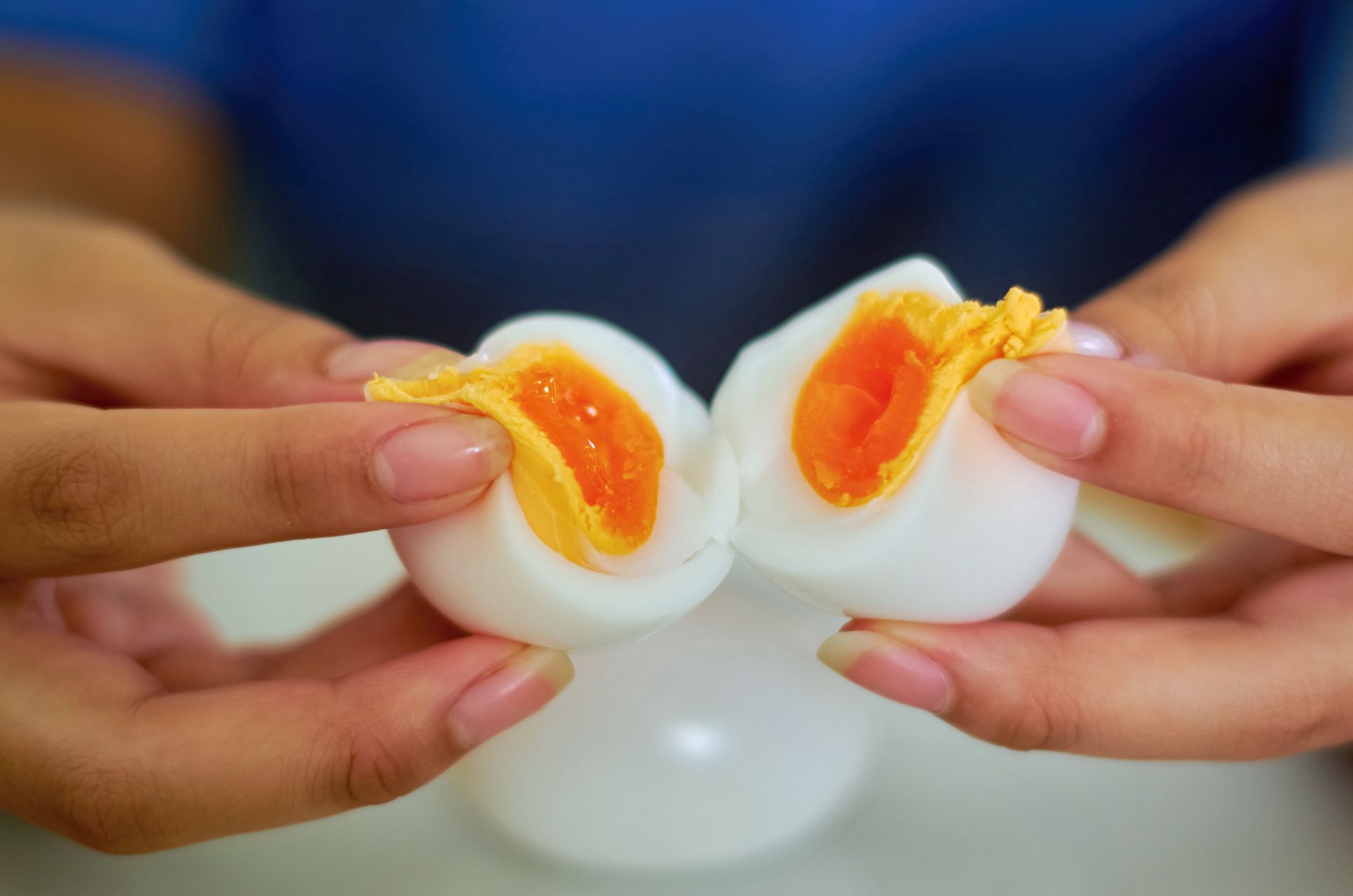 Hands Cracking Open a Soft-Boiled Egg Revealing a Perfectly Juicy Yolk
A close-up view of two hands gently splitting a soft-boiled egg, revealing its golden, runny yolk. The image showcases the delicate texture of the egg, with the creamy yolk oozing out against the smooth, cooked egg white.
Krit of Studio OMG