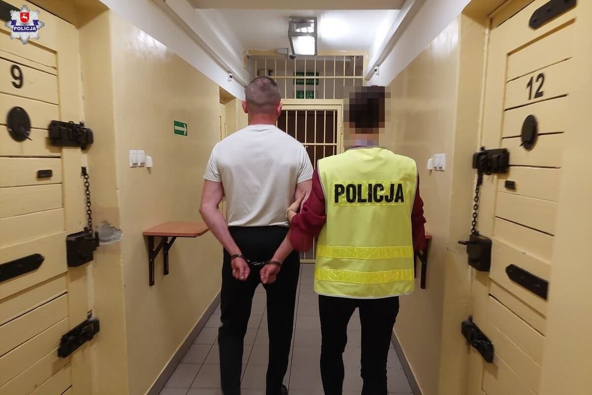 Policjant prowadzi zatrzymanego z kajdankami na rękach