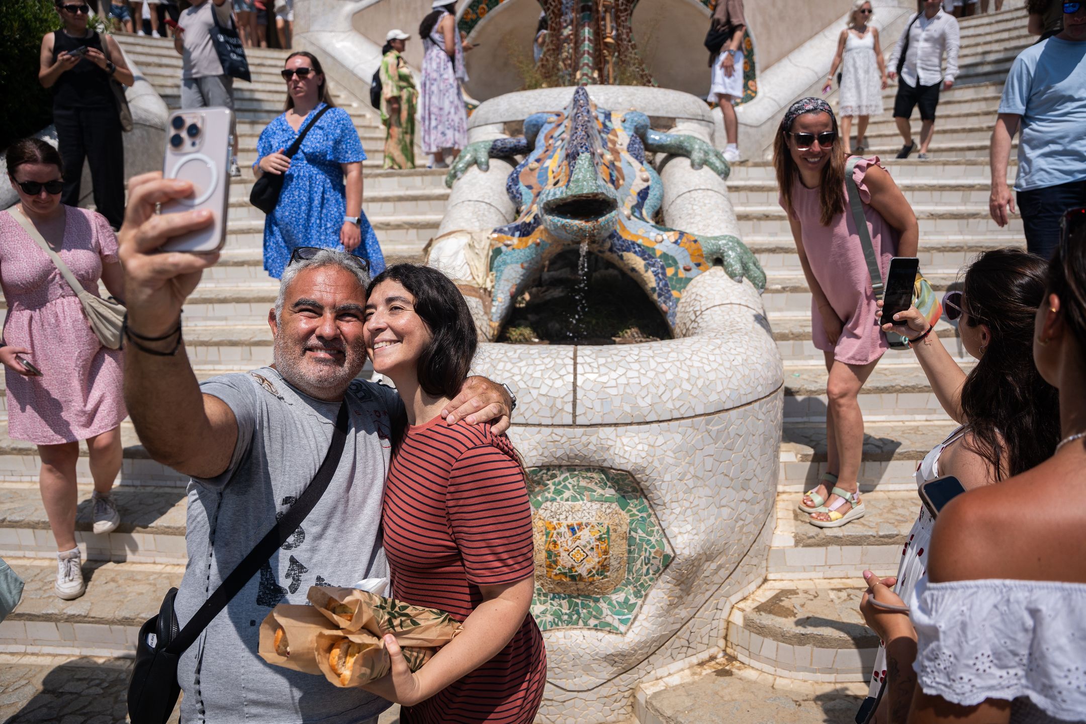 Overtourism At Park Guell In Barcelona.
Tourists stroll through Park Guell and take pictures with Antoni Gaudi's architecture and the famous ''Park Guell Lizard'' during a hot morning in Barcelona, Spain, on July 6, 2025. The Catalan capital receives 20.37 million tourists annually, equivalent to a density of 201,722 visitors per square kilometer, making Barcelona the most crowded and tourist-filled city in the world. (Photo by Marc Asensio/NurPhoto via Getty Images)
NurPhoto
vacation, touristification, asian tourism, itinerary, overcrowding, tour guide, getaway, world, heritage, historical interest, trip, mobile, destination, mass tourism, china, la salut neighborhood, heat, barcelona