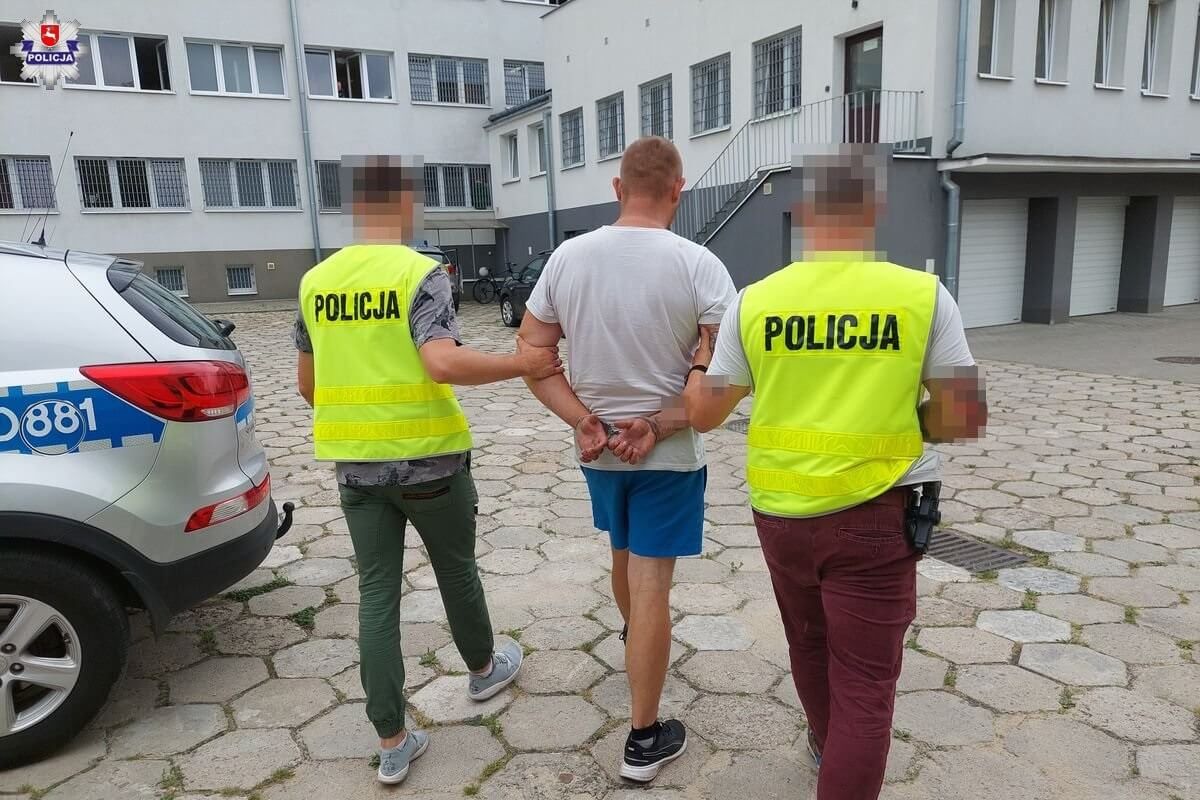 Policjanci prowadzą zatrzymanego z kajdankami na rękach
