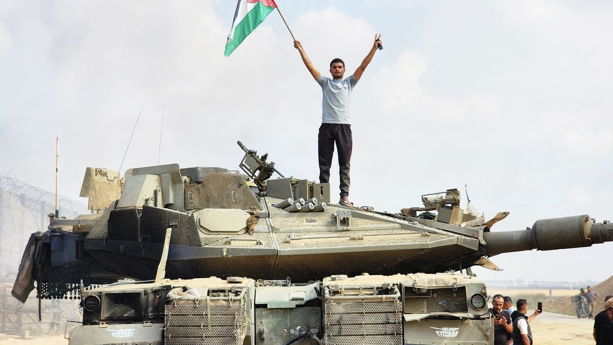GAZA CITY, GAZA - OCTOBER 07: Hamas' armed wing, the Izz ad-Din al-Qassam Brigades hold a Palestinian flag as they destroy a tank of Israeli forces in Gaza City, Gaza on October 07, 2023. (Photo by Hani Alshaer/Anadolu Agency via Getty Images)