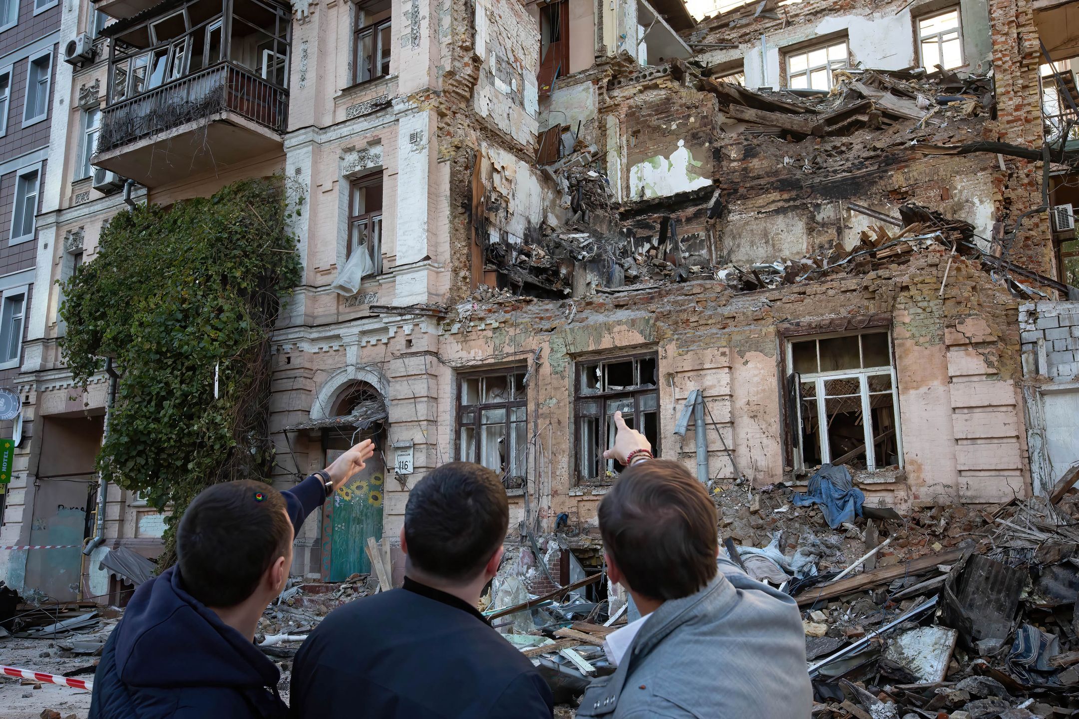 KYIV, UKRAINE - 2022/10/18: People look at the residential building destroyed by a Russian drone strike, which local authorities consider to be Iranian-made unmanned aerial vehicles (UAVs) Shahed-136, in central Kyiv. At least four people have been killed as a result of a drone attack on a residential building in Kyiv on the morning of October 17, 2022. (Photo by Oleksii Chumachenko/SOPA Images/LightRocket via Getty Images)