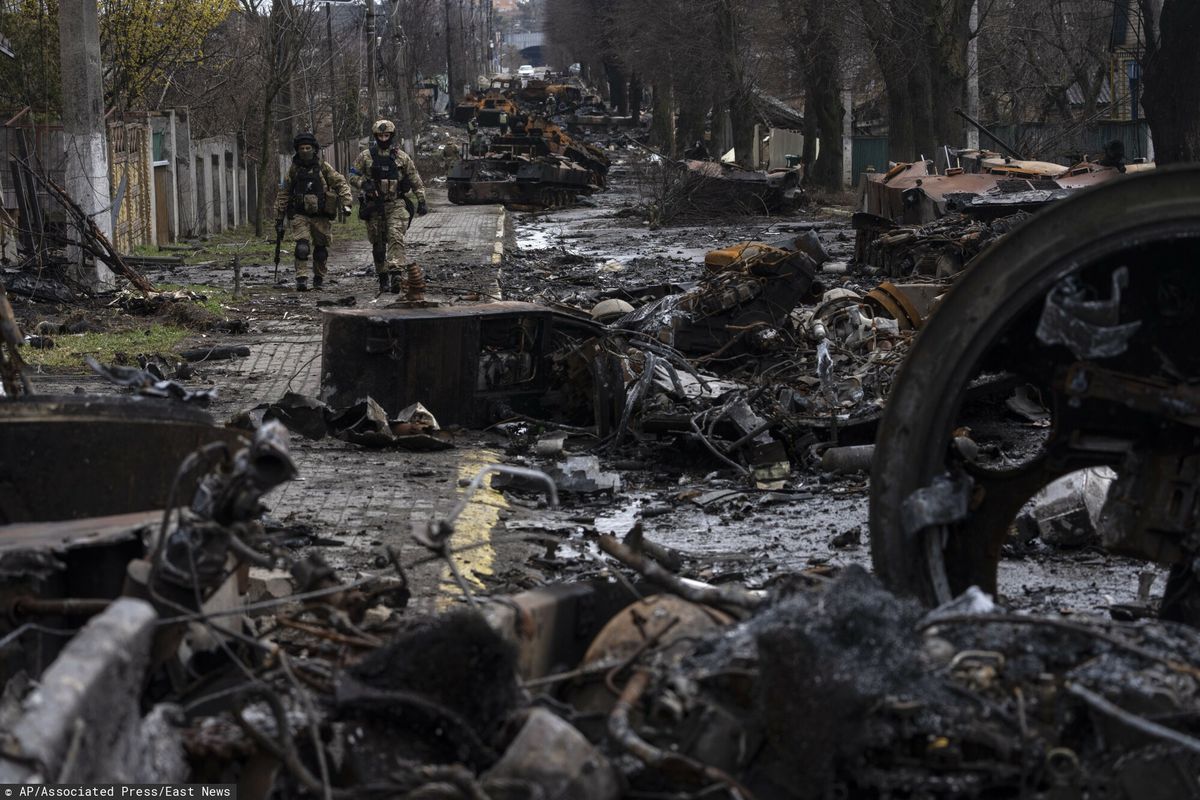 Ukraińscy żołnierze przechodzą przez ulicę pełną zniszczonych rosyjskich czołgów w podkijowskiej Buczy 