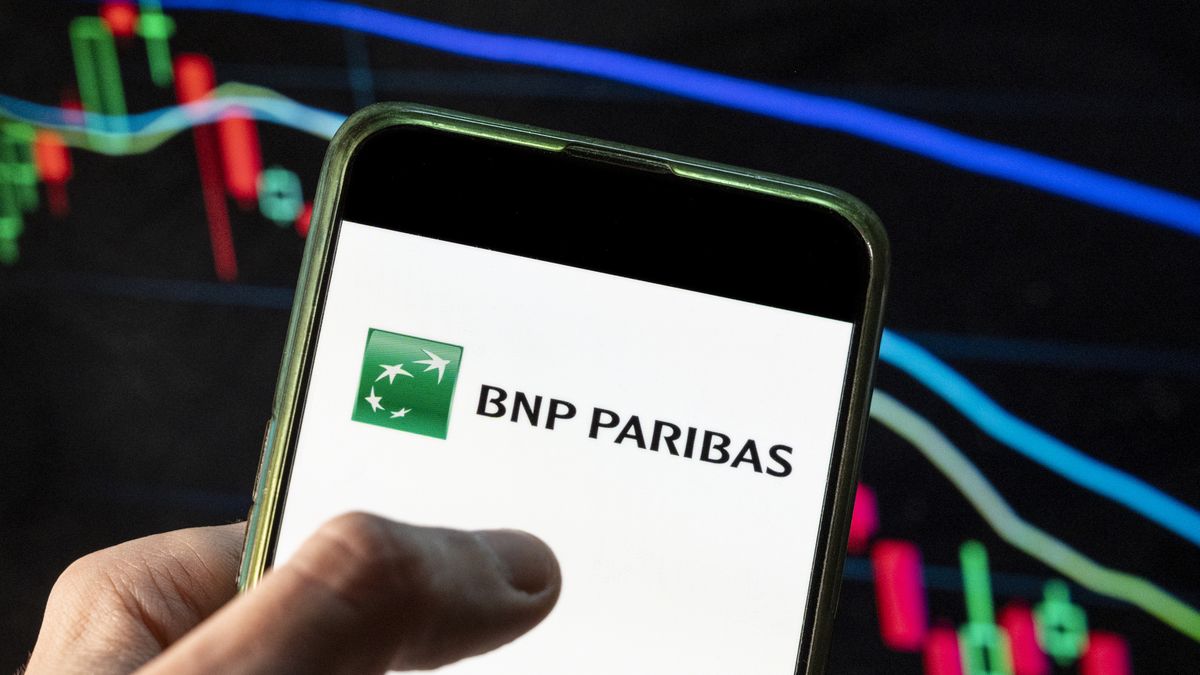 CHINA - 2021/12/09: In this photo illustration the French international banking group BNP Paribas logo seen displayed on a smartphone with an economic stock exchange index graph in the background. (Photo Illustration by Budrul Chukrut/SOPA Images/LightRocket via Getty Images)