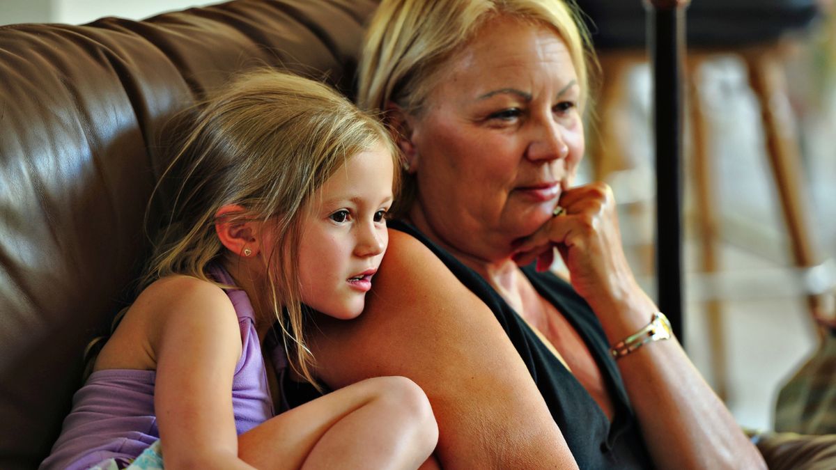 Babcia i wnuczka siedzą na sofie i oglądają telewizję