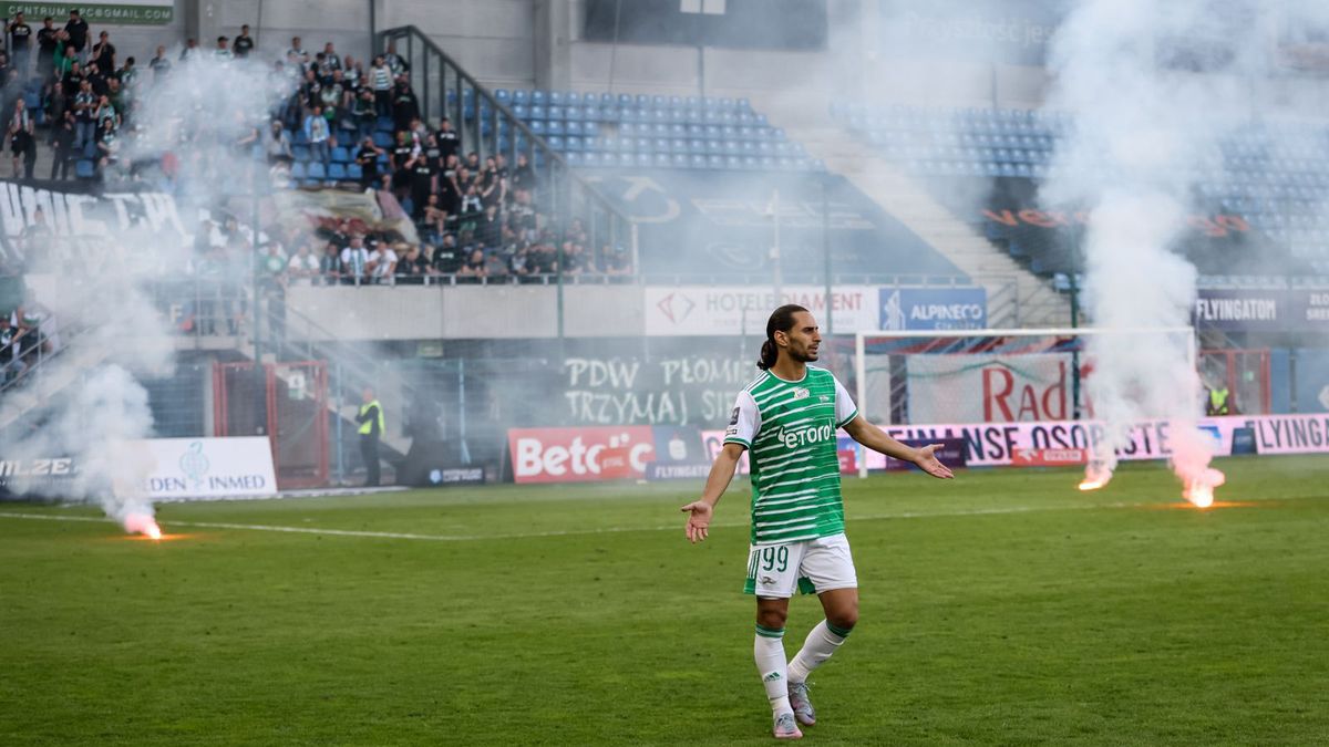 Ilkay Durmus, piłkarz Lechii Gdańsk; w tle race rzucone na murawę przez fanów Lechii