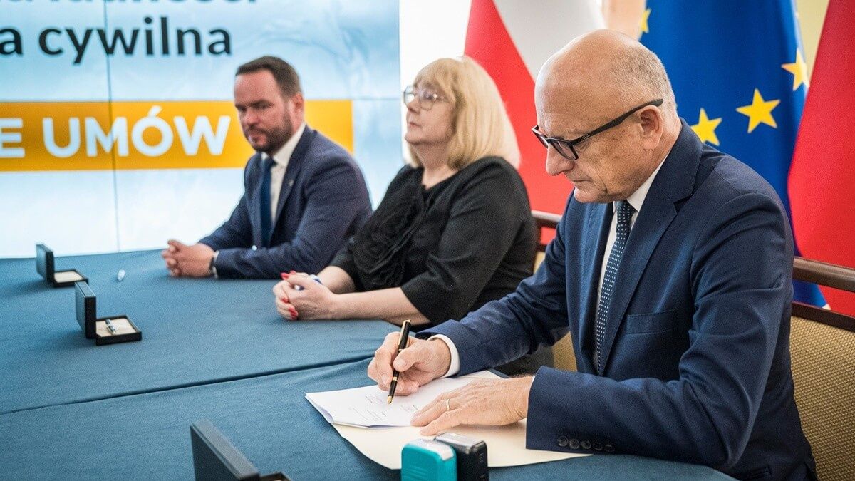 Krzysztof Żuk podpisujący umowy