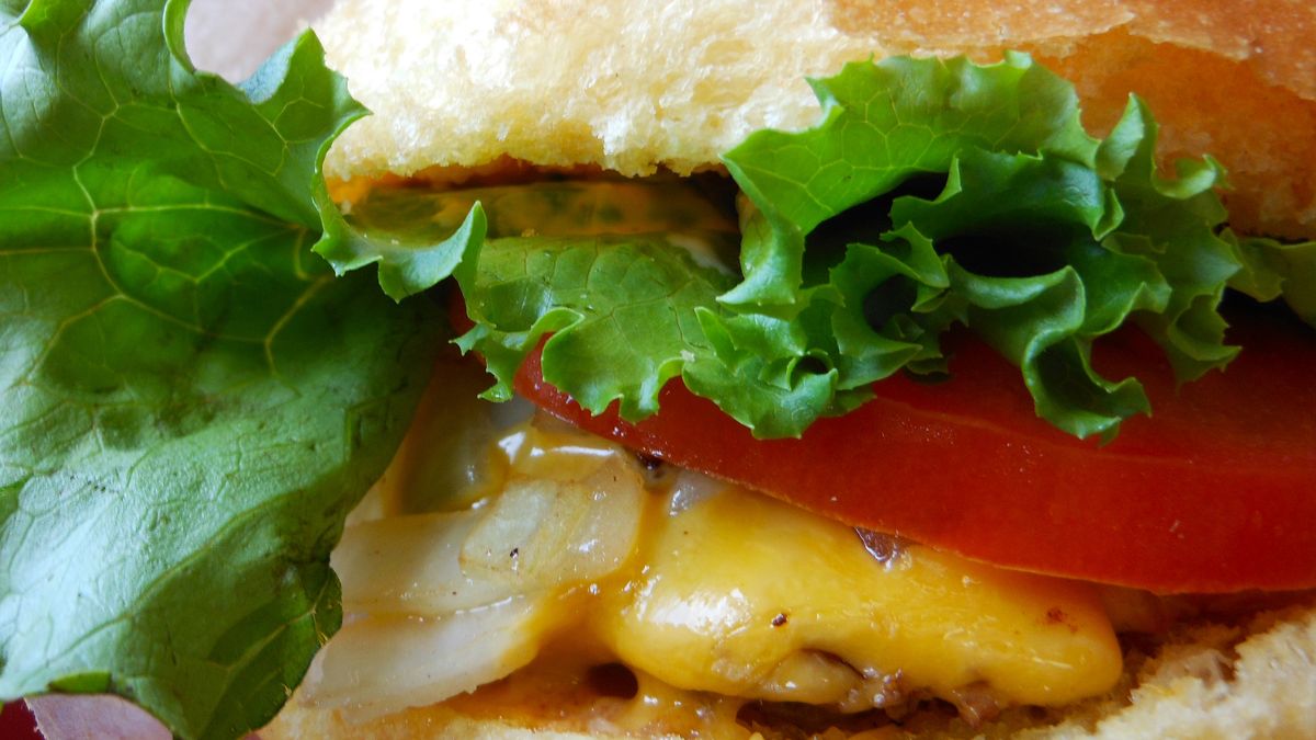 Powiększony cheeseburger z przyprawami, warzywami i szynką