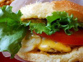 Powiększony cheeseburger z przyprawami, warzywami i szynką