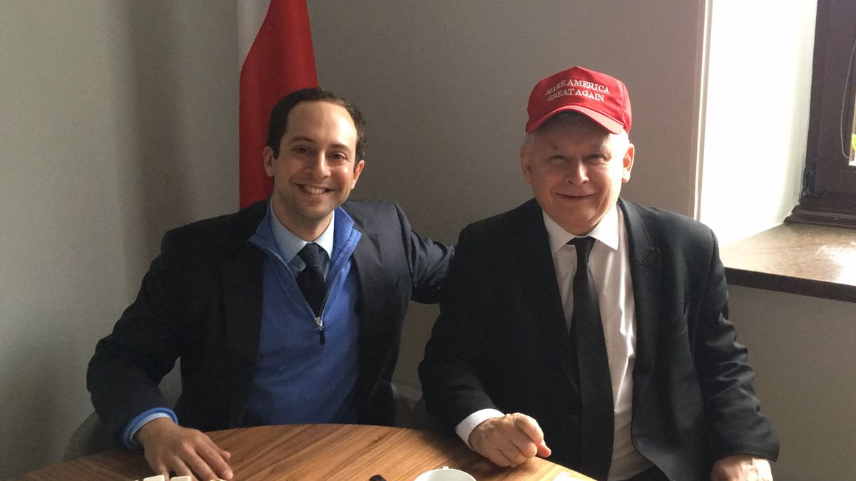 Uśmiechnięty Jarosław Kaczyński w czapeczce Donalda Trumpa