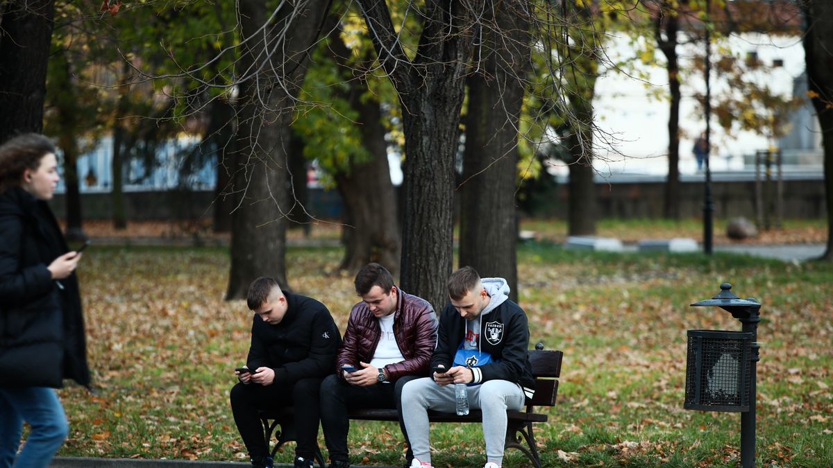 Young men are seen using mobile phones in a park in central Warsaw, Poland on 03 November, 2021. (Photo by STR/NurPhoto via Getty Images)