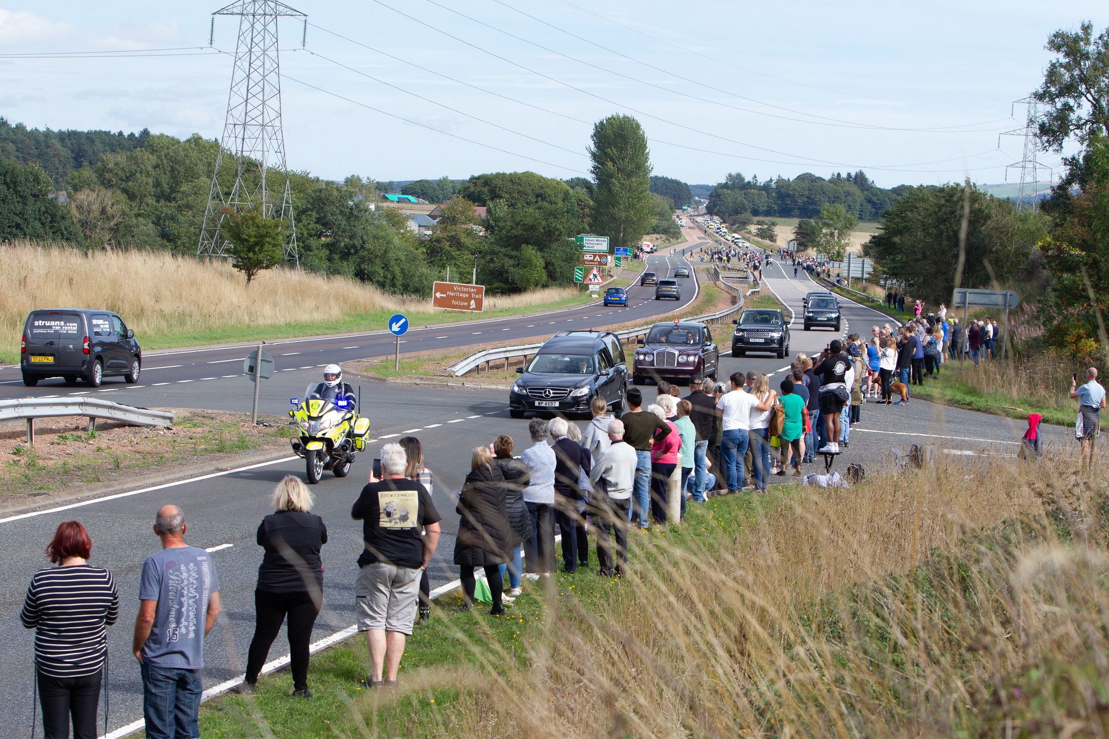People stand to pay their respects as the hearse carrying the body of Queen Elizabeth II makes its way towards Edinburgh, on the A90 in Stracathro, Angus county, Scotland, Britain, 11 September 2022. Britain's Queen Elizabeth II died at her Scottish estate on 08 September. The late queen will lie in state for 24 hours at St Giles' Cathedral in Edinburgh. EPA/PAUL REID Dostawca: PAP/EPA.