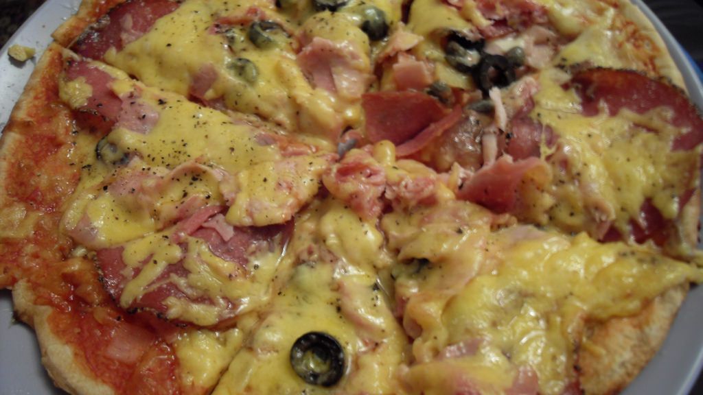 Upieczona mrożona pizza z mięsem i warzywami na grubym cieście