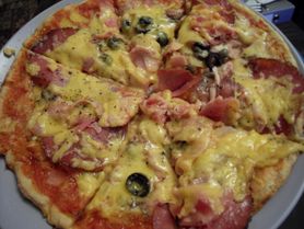 Upieczona mrożona pizza z mięsem i warzywami na grubym cieście