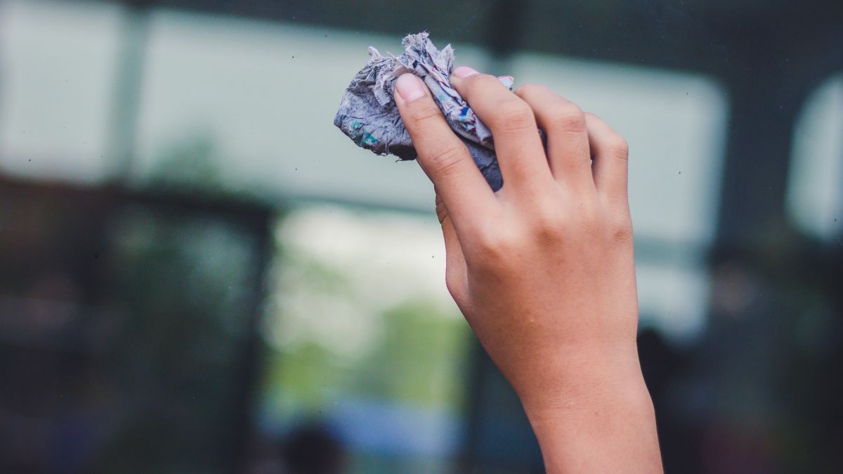 Kobieta myje szybę gazetą