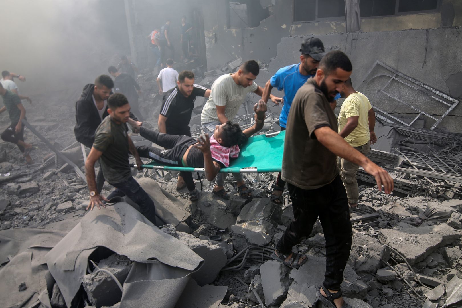 RAFAH, GAZA - OCTOBER 12: People carry an injured man on a stretcher among rubbles of destroyed buildings as Israeli airstrikes continue on the sixth day in Rafah, Gaza on October 12, 2023. (Photo by Abed Rahim Khatib/Anadolu via Getty Images)