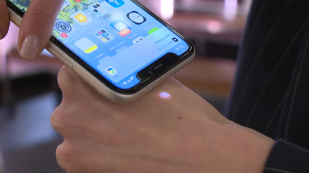 Telefon zbliżony do dłoni z chipem covidowym