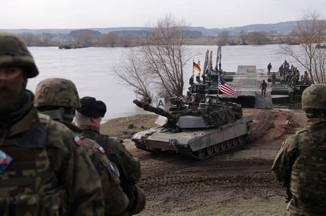 GNIEW, POLAND - MARCH 04: Polish soldiers stand by as a M1 Abrams main battle tank of the U.S. Army descends from M3 amphibious rigs of the German/British Amphibious Engineer Battalion 130 after crossing the Vistula River during the NATO Dragon 24 military exercise on March 04, 2024 near Gniew, Poland. Dragon 24 is involving 20,000 troops from 10 different nations and is part of Steadfast Defender 2024, an ongoing set of NATO military manoeuvres across Europe that is involving 90,000 troops. (Photo by Sean Gallup/Getty Images)