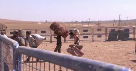 Uchodźcy z Syrii przekraczają prowizoryczny punkt kontrolny na granicy z Turcją