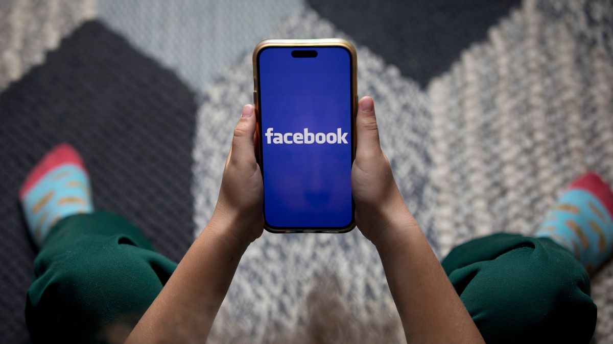 A child holds a smartphone displaying the Facebook logo in an arranged photograph in Sydney, Australia, on Wednesday, Dec. 3, 2025. Australia will soon ban its youth from popular services like TikTok and Instagram, becoming the world's first democracy to carry out such a crackdown in response to growing concerns about social media's harms. Photographer: Brent Lewin/Bloomberg via Getty Images