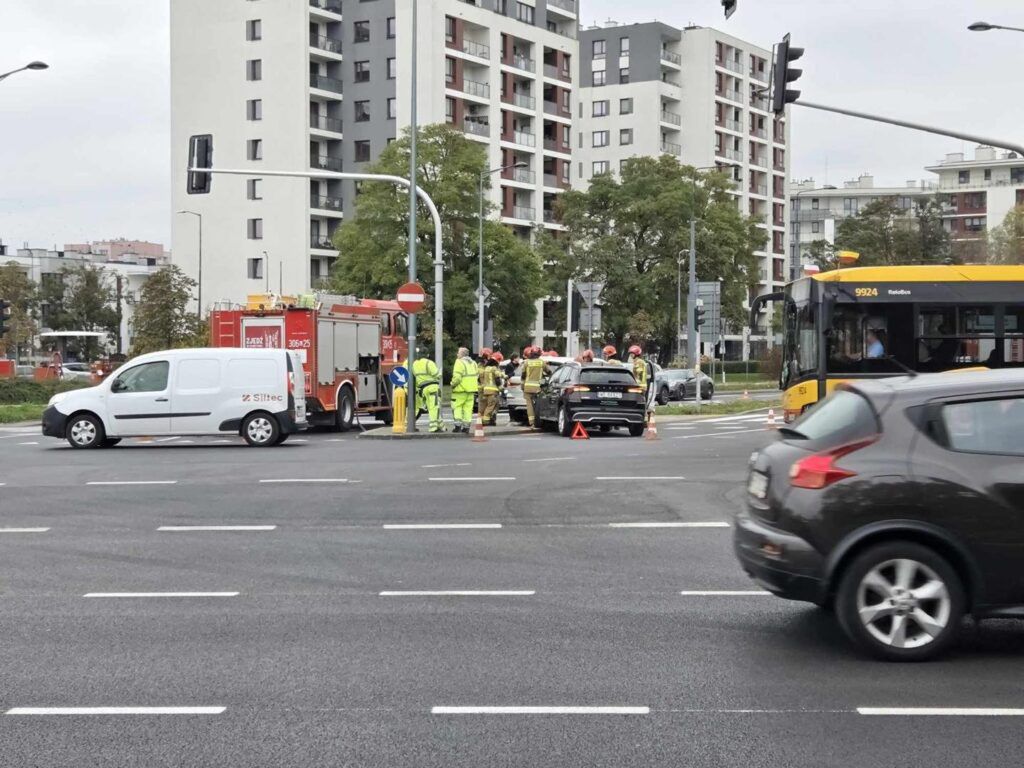 Grupa ratowników w odzieży ochronnej pracuje przy wypadku drogowym na ruchliwym skrzyżowaniu.