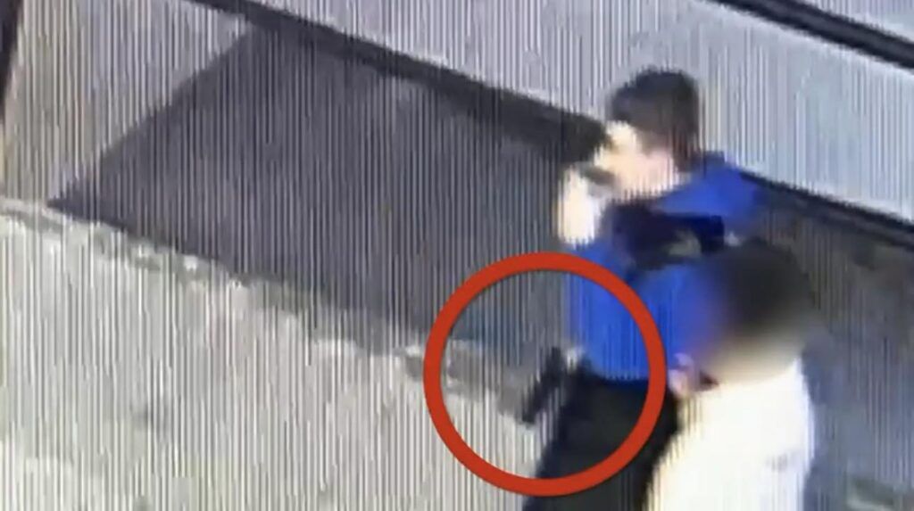 Mężczyzna w niebieskiej koszuli trzyma telefon przy uchu, stojąc obok drugiej osoby w jasnej odzieży.