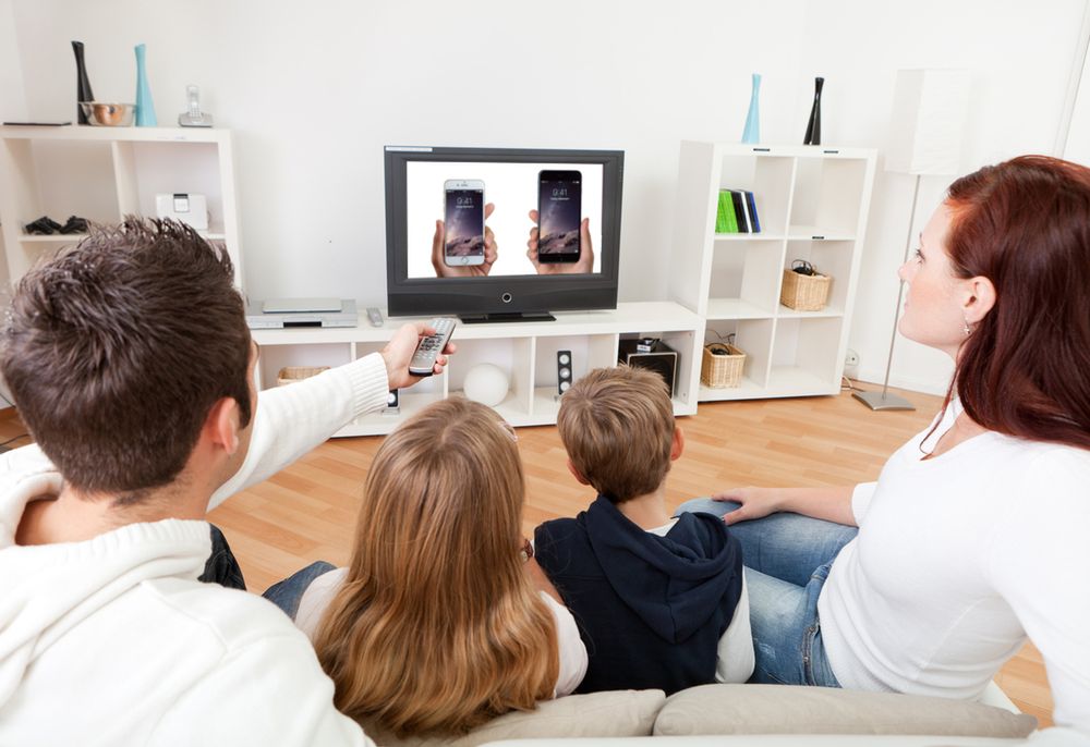 Zmodyfikowane zdjęcie Young family watching TV together at home