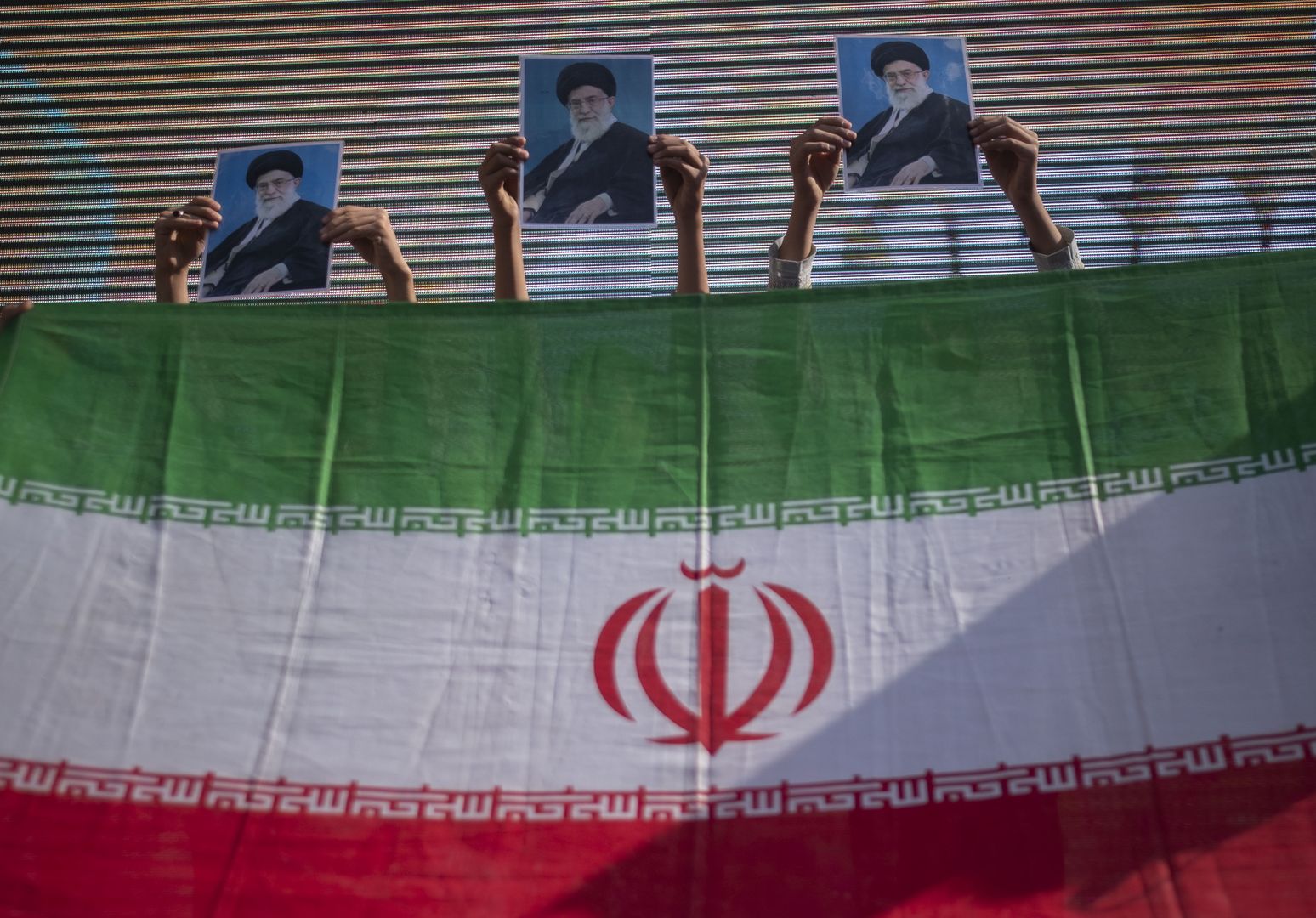 A group of young Iranian schoolboys standing behind an Iran flag hold-up portraits of Iran's Supreme Leader, Ayatollah Ali Khamenei, while performing in an anti-Israel rally protesting the Israeli air strike on Al-Ahli hospital, in northern Tehran, October 20, 2023. Israel's military denied responsibility for the Gaza hospital attack, attributing it to a failed rocket launch by the Palestinian Islamic Jihad group. MORTEZA NIKOUBAZL/NurPhoto (Photo by Morteza Nikoubazl/NurPhoto via Getty Images)