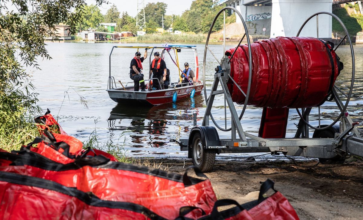 Szczecin, 17.08.2022. Strażacy stawiają zaporę elastyczną mającą za zadanie wyłapywanie śniętych ryb na Odrze w dzielnicy Szczecin Dziewoklicz