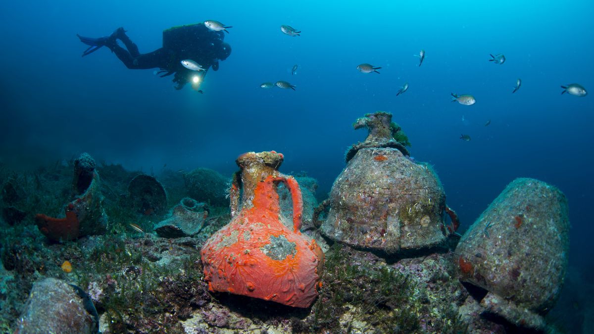 IZMIR, TURKIYE - OCTOBER 20: A scuba diver explores ancient amphorae on the seabed off the coast of Cesme, a prominent diving destination known for its rich marine fauna and flora, tuna farms, ray species, and shipwrecks in Izmir, Turkiye, on October 20, 2025. The area, which attracts many diving enthusiasts every year, is also home to longtail stingrays, a species rarely observed in Turkish waters. The Monem Wreck, suitable for divers of all levels, offers visitors an impressive diving experience with high underwater visibility. Tuna farms, accessible only with special permission, are among the habitats of Mediterranean bluefin tuna. In the blue depths of Cesme, octopuses and other marine creatures also appear before the lenses of diving enthusiasts. (Photo by Tahsin Ceylan/Anadolu via Getty Images)